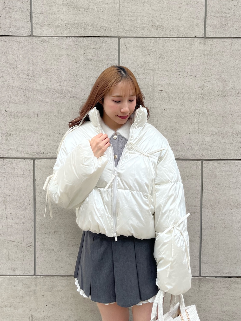 ホワイト系のダウンジャケット/コート、グレー系のカーディガン/ボレロ、グレー系のスカートを着用したレディースの秋コーディネートの2枚目の写真