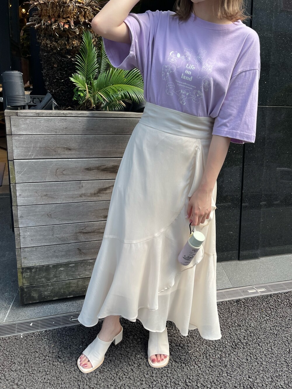 パープル系のTシャツ/カットソー、ベージュ系のスカート、ホワイト系のサンダルを着用したレディースの夏コーディネートの2枚目の写真