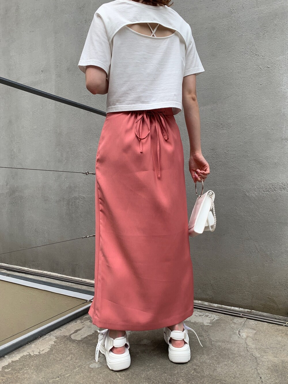 ホワイト系のTシャツ/カットソー、ピンク系のスカート、ホワイト系のサンダルを着用したレディースの夏コーディネートの3枚目の写真