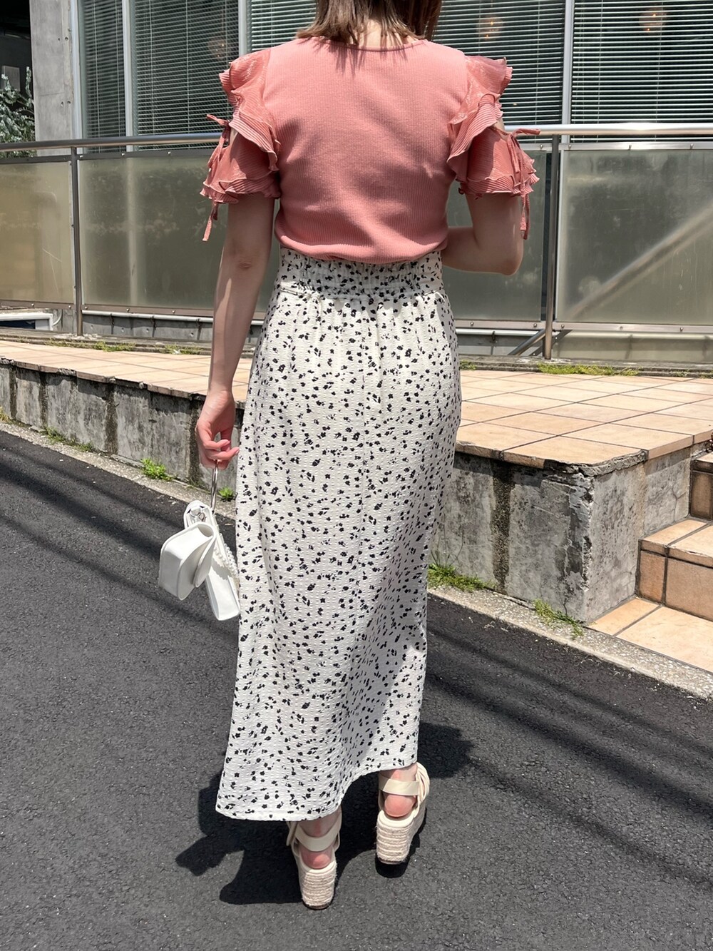 オレンジ系のTシャツ/カットソー、ホワイト系のスカート、ホワイト系のショルダーバッグを着用したレディースの春コーディネートの2枚目の写真