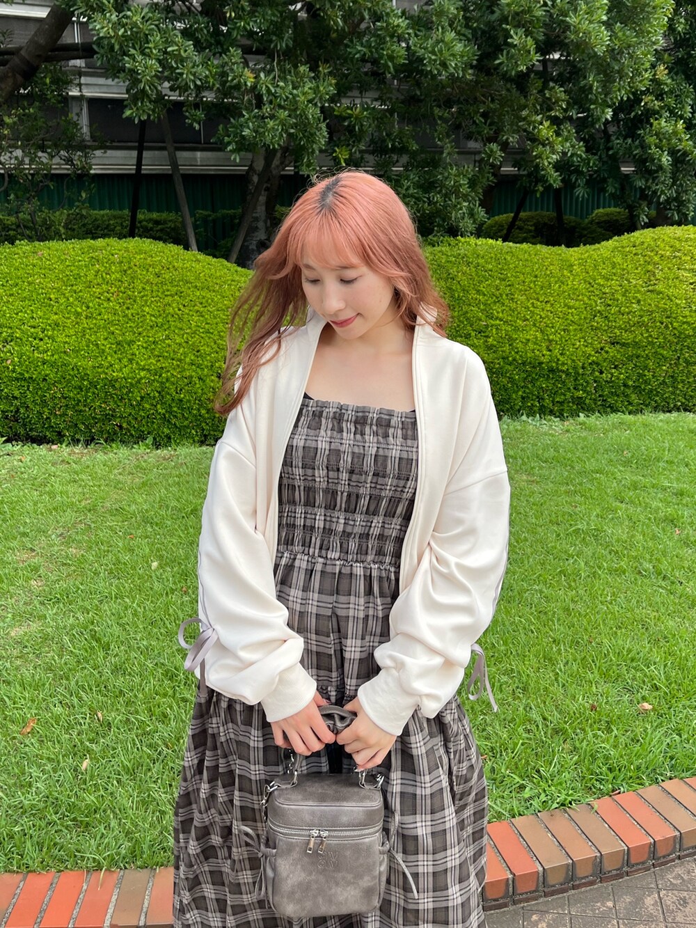 ブラウン系のワンピース、ホワイト系のジャージ、ブラック系のショルダーバッグを着用したレディースの夏コーディネートの2枚目の写真