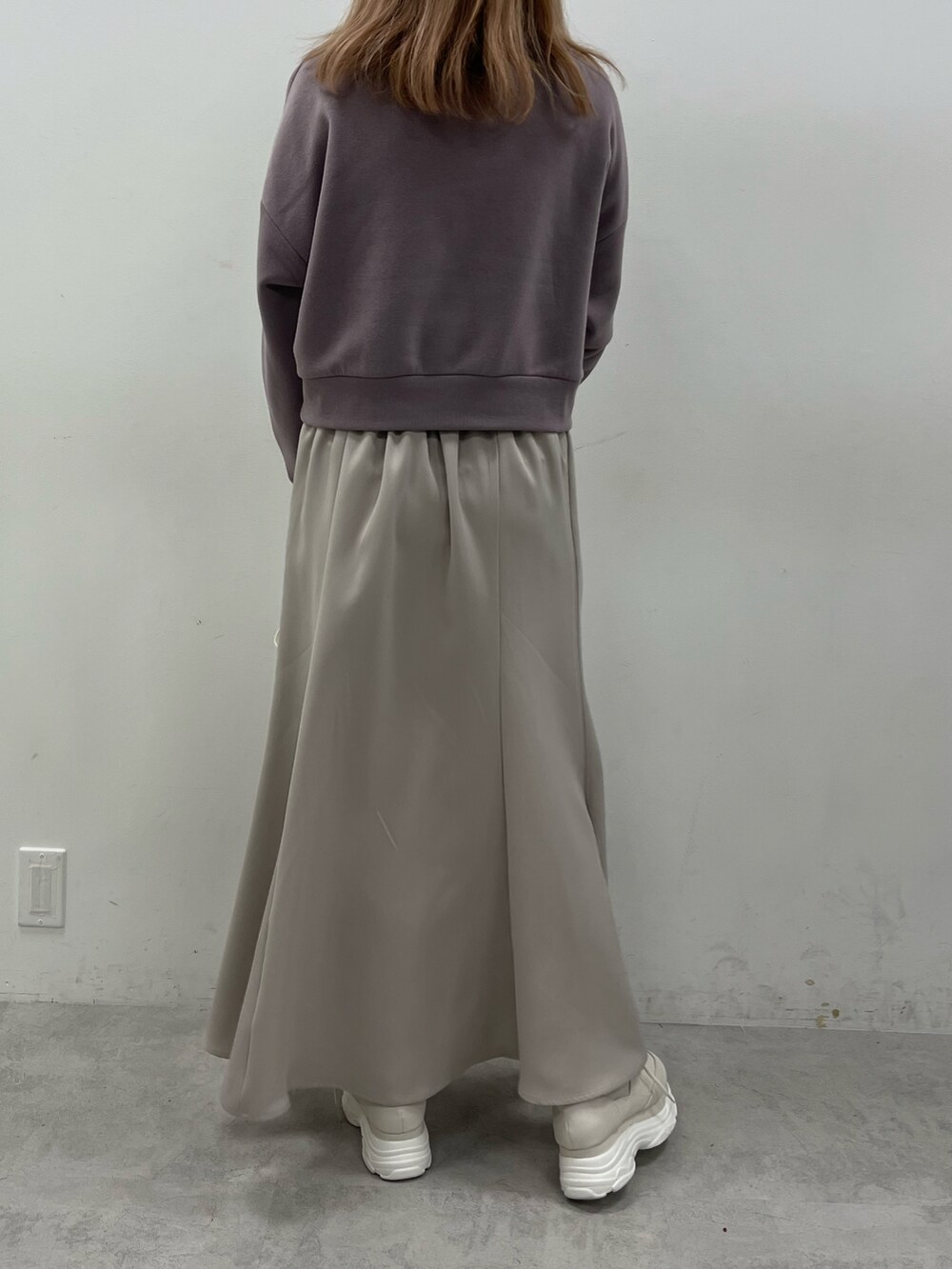 パープル系のスウェット、ベージュ系のスカート、ホワイト系のスニーカーを着用したレディースの冬コーディネートの2枚目の写真