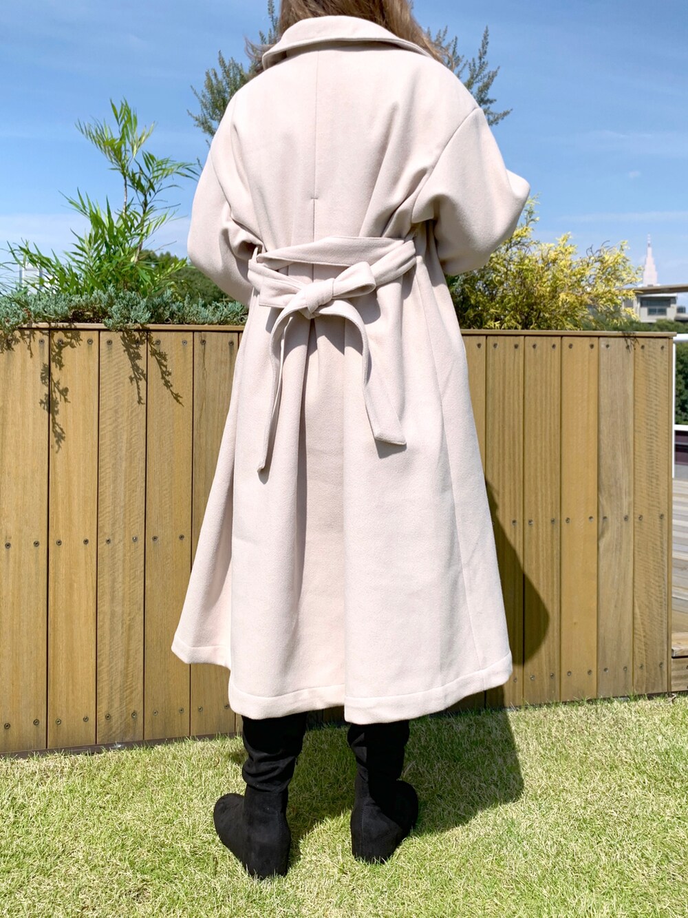 ベージュ系のステンカラーコート、ブラック系のTシャツ/カットソー、ブラック系のブーツを着用したレディースの秋コーディネートの2枚目の写真