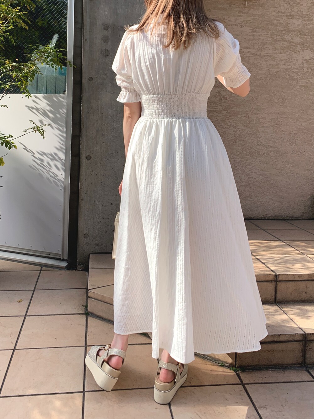 ホワイト系のワンピース、ホワイト系のショルダーバッグ、ゴールド系のサンダルを着用したレディースの春コーディネートの3枚目の写真