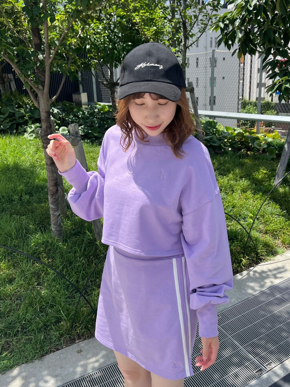 パープル系のスウェット、パープル系のスカート、ブラック系のスニーカーを着用したレディースの夏コーディネートの3枚目の写真