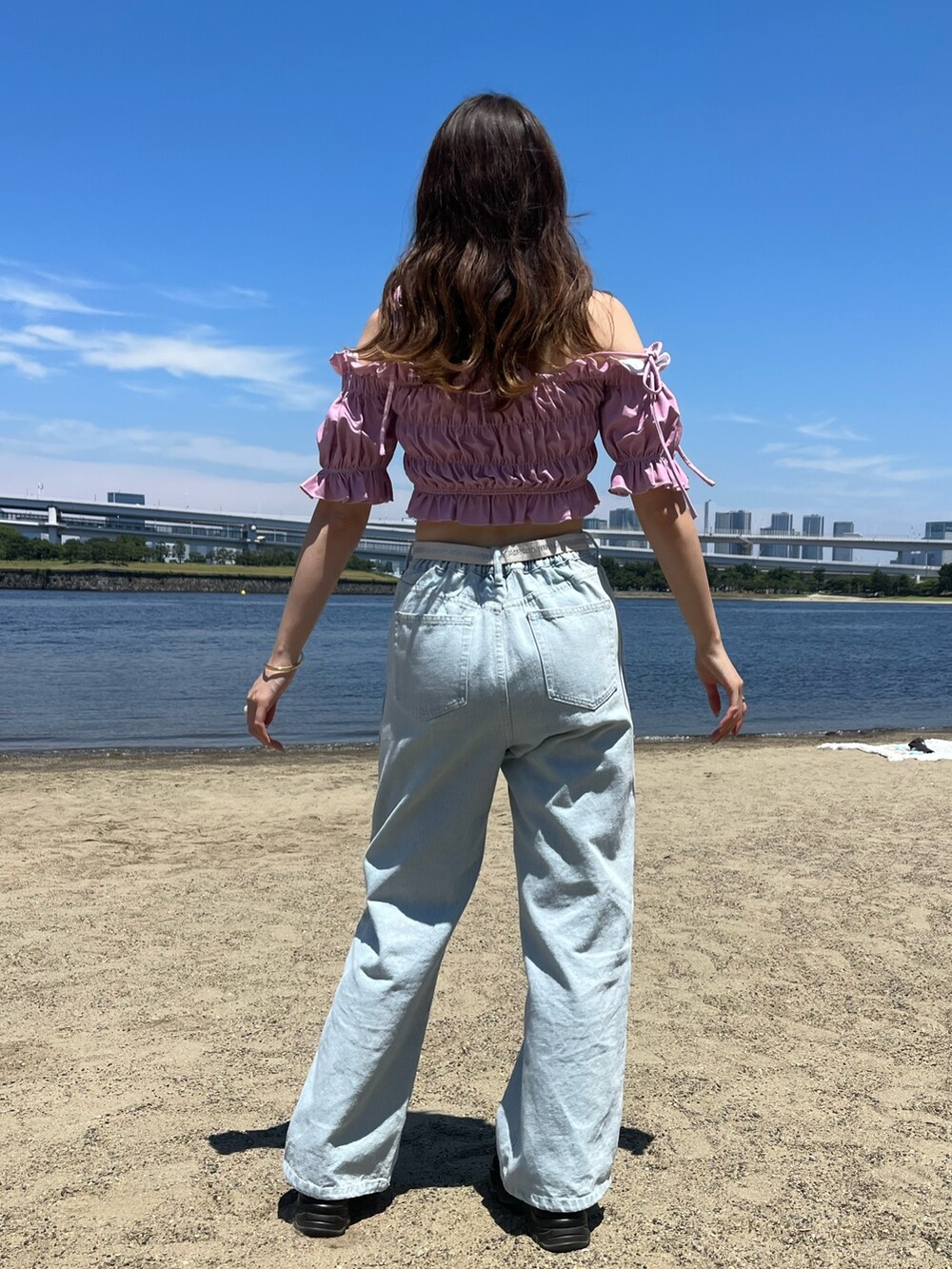 ブルー系のデニムパンツ、ブラック系のサンダル、ピンク系の水着を着用したレディースの夏コーディネートの2枚目の写真