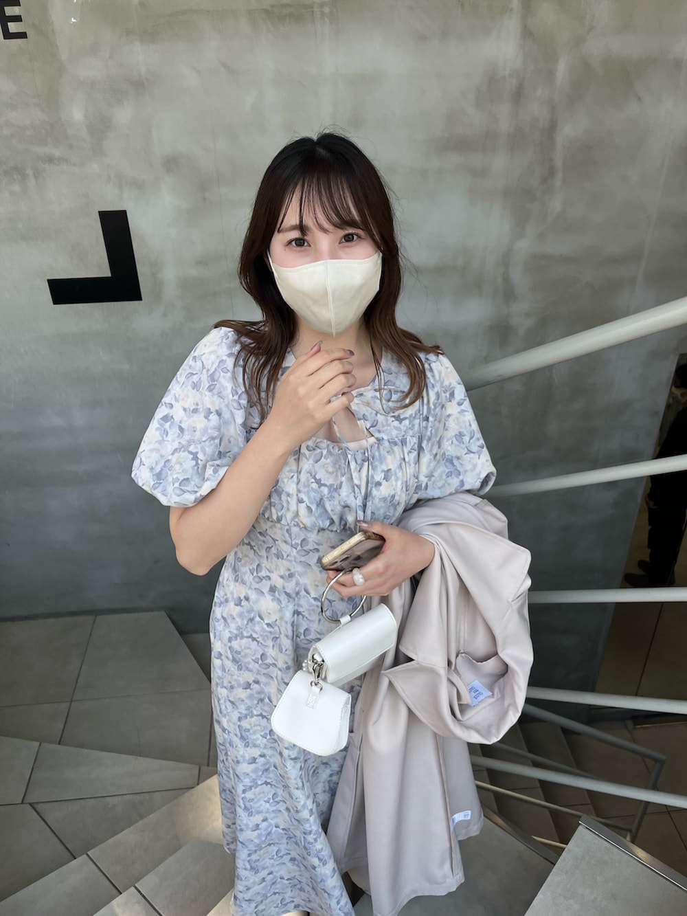 グレー系のワンピース、ベージュ系のトレンチコート、ホワイト系のサンダルを着用したレディースの春コーディネートの3枚目の写真