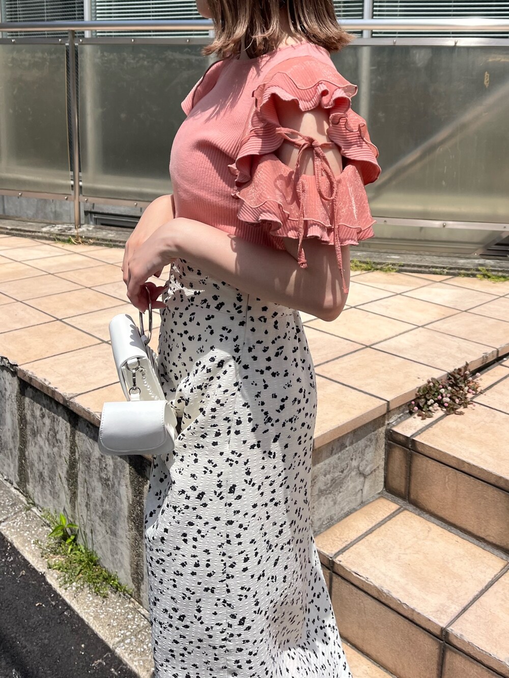 オレンジ系のTシャツ/カットソー、ホワイト系のスカート、ホワイト系のショルダーバッグを着用したレディースの春コーディネートの3枚目の写真