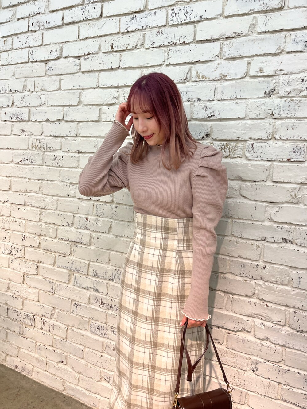 ブラウン系のニット/セーター、ブラウン系のスカート、ブラウン系のショルダーバッグを着用したレディースの秋コーディネートの2枚目の写真