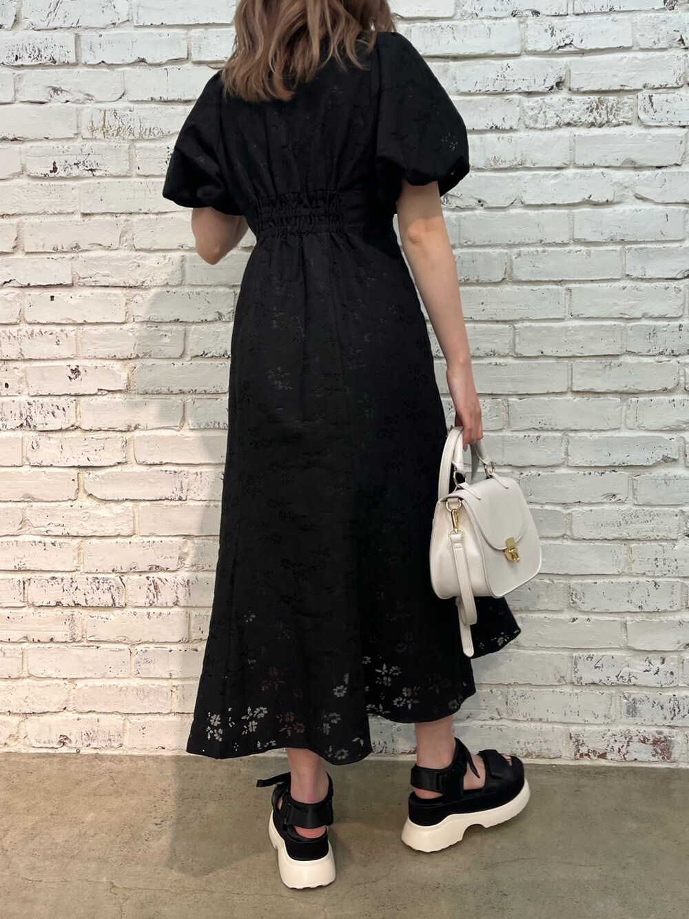 ブラック系のワンピース、ホワイト系のショルダーバッグ、ブラック系のサンダルを着用したレディースの春コーディネートの3枚目の写真
