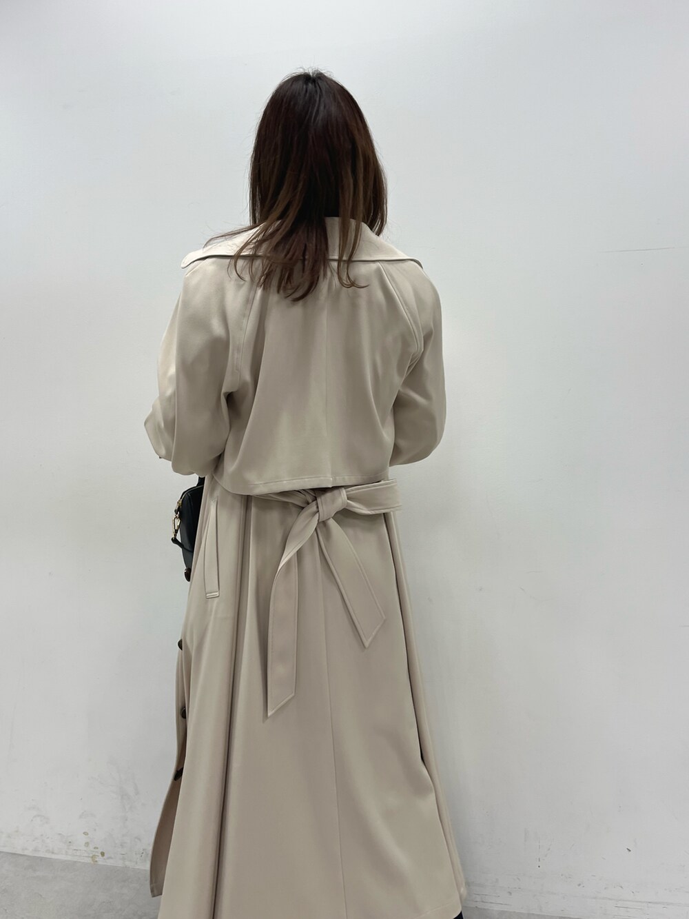 ベージュ系のトレンチコート、ブラック系のTシャツ/カットソー、ブルー系のスカートを着用したレディースの冬コーディネートの2枚目の写真