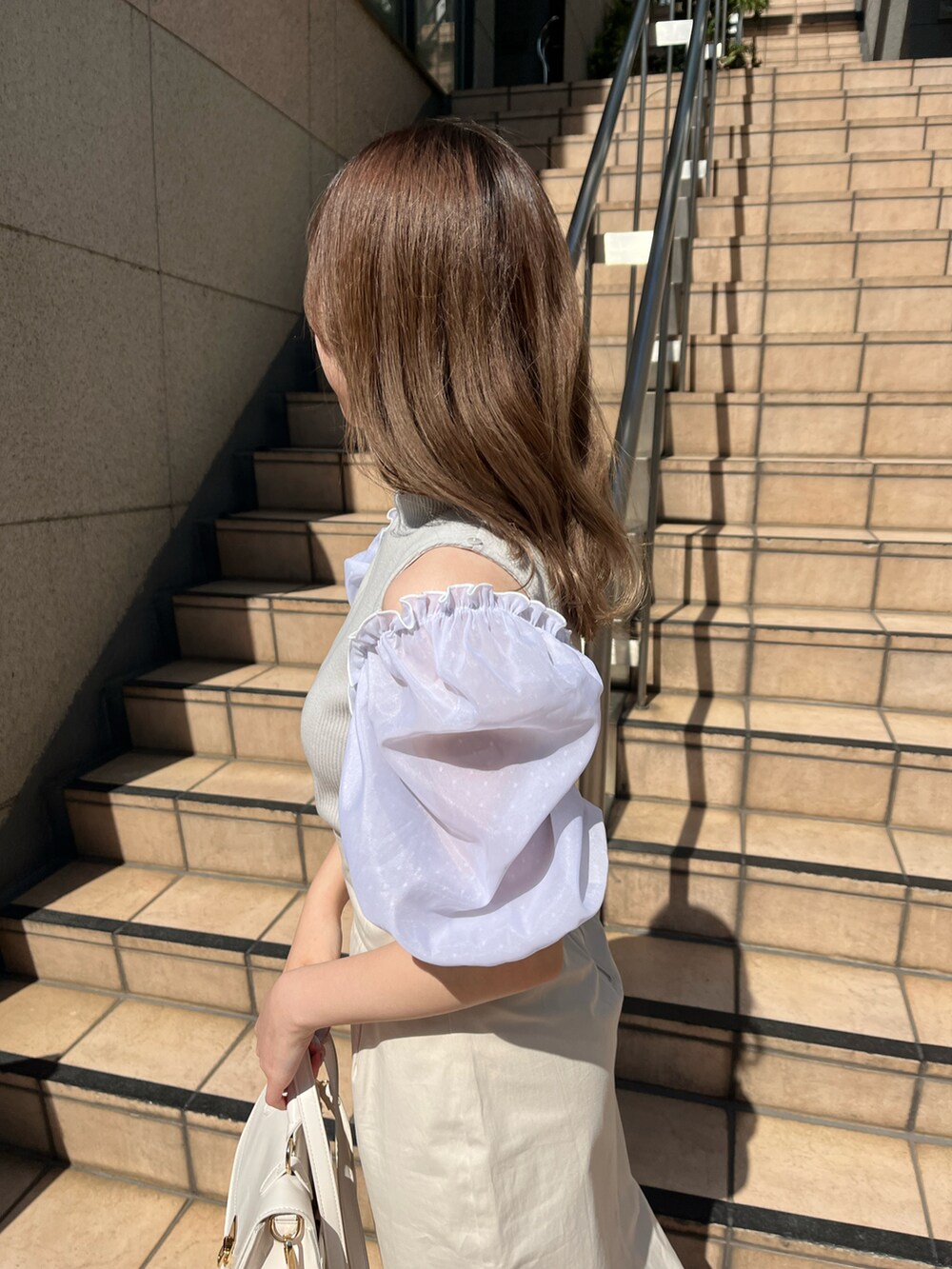 グレー系のTシャツ/カットソー、ホワイト系のスカート、ホワイト系のショルダーバッグを着用したレディースの春コーディネートの3枚目の写真