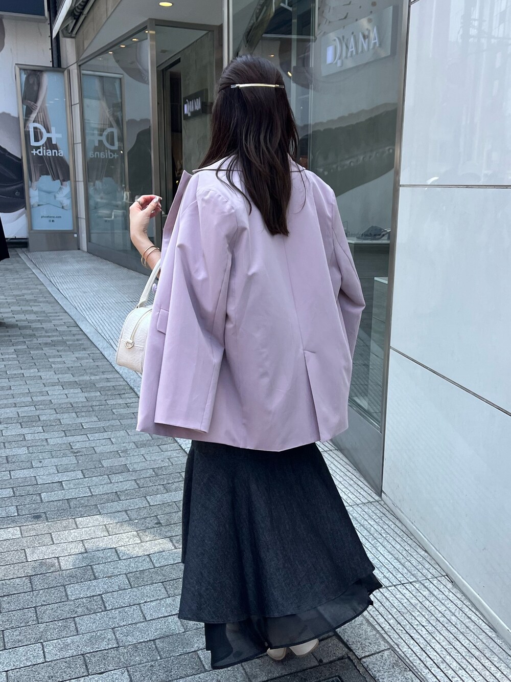 ピンク系のテーラードジャケット、ブラック系のワンピース/ドレス、ホワイト系のショルダーバッグを着用したレディースの夏コーディネートの2枚目の写真