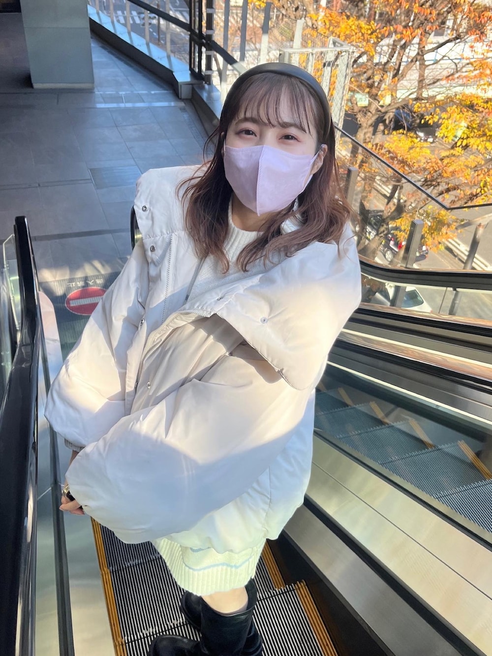 ブラック系のダウンジャケット/コート、ブラック系のブーツ、ブルー系のニット/セーターを着用したレディースの冬コーディネートの2枚目の写真