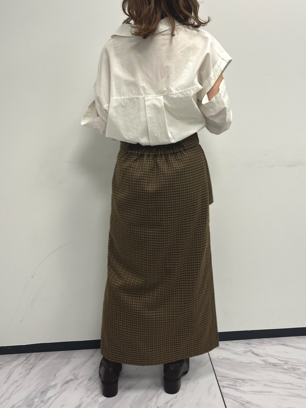 ホワイト系のシャツ/ブラウス、ブラウン系のスカート、ブラウン系のブーツを着用したレディースの夏コーディネートの2枚目の写真