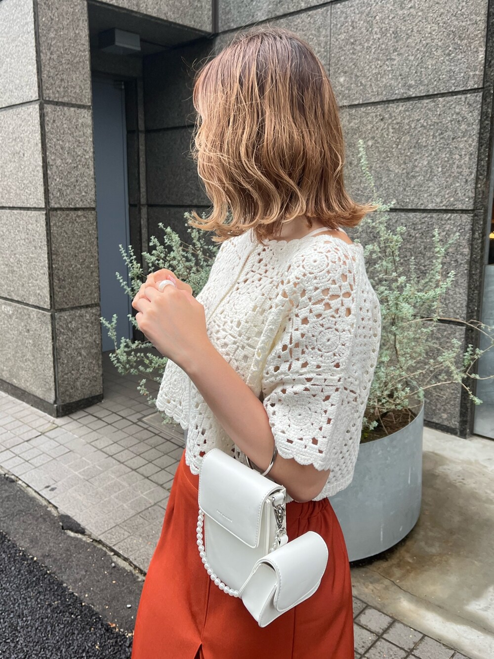 ホワイト系のカーディガン/ボレロ、オレンジ系のスカート、ベージュ系のサンダルを着用したレディースの夏コーディネートの2枚目の写真