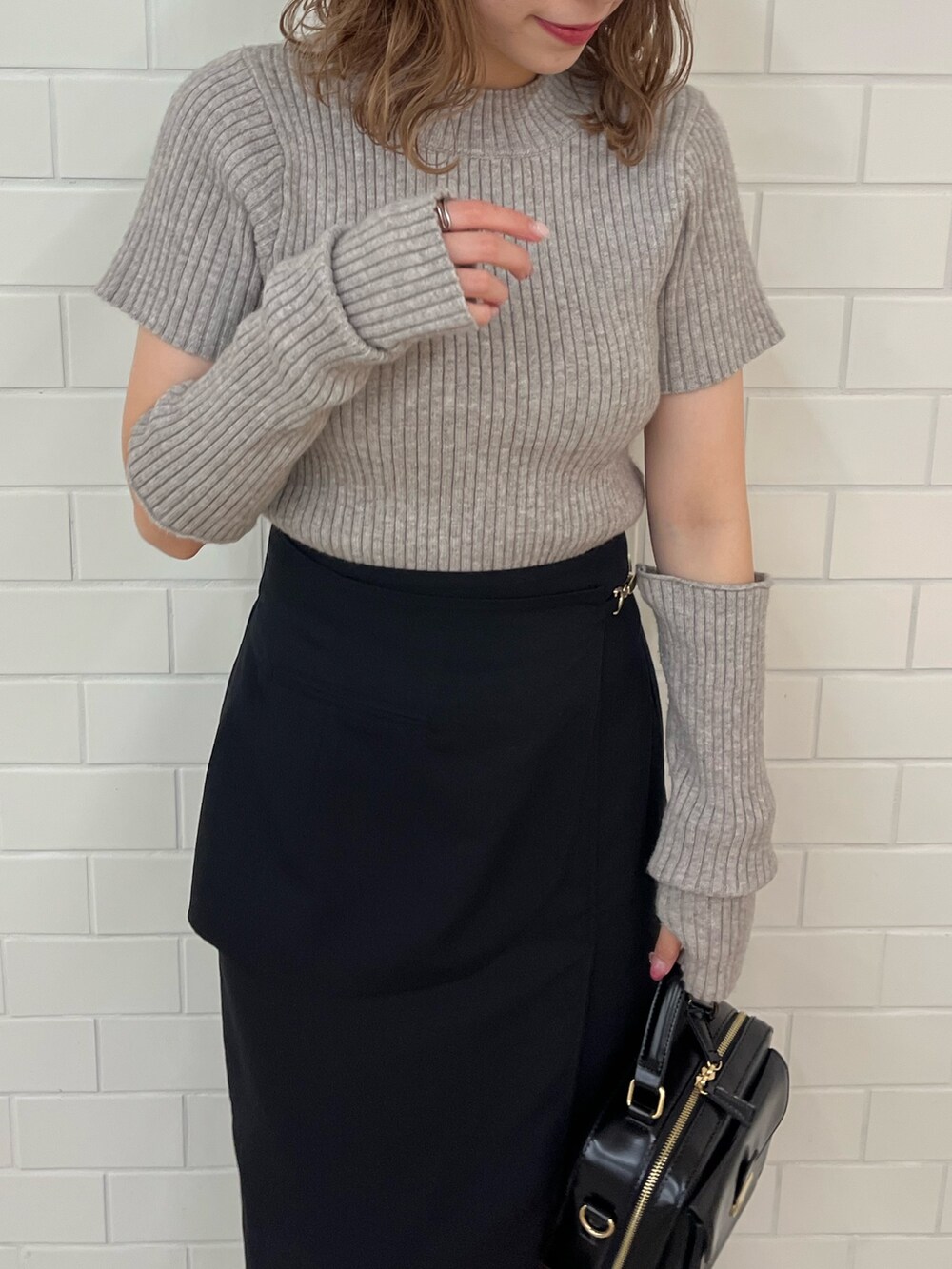 ブラウン系のニット/セーター、ブラック系のスカート、ホワイト系のスニーカーを着用したレディースの夏コーディネートの3枚目の写真