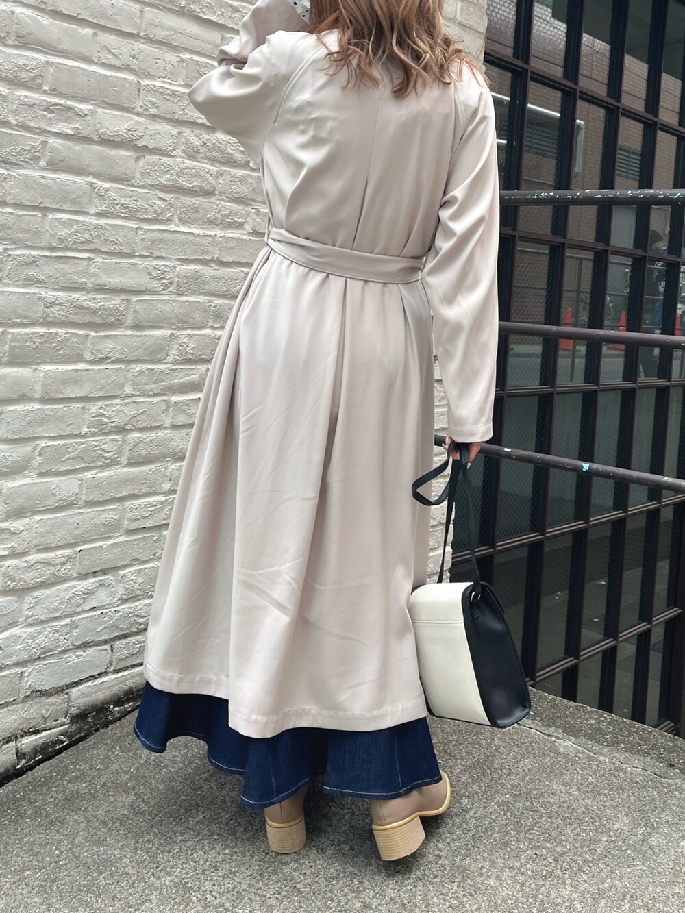 ホワイト系のトレンチコート、ブラック系のショルダーバッグ、ベージュ系のブーツを着用したレディースの冬コーディネートの2枚目の写真