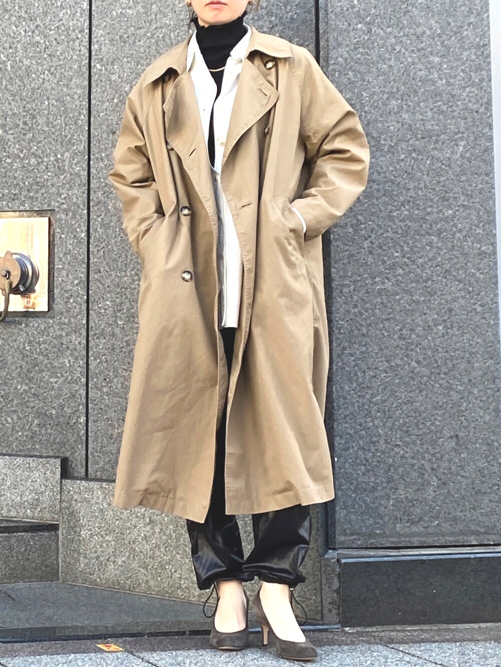 ベージュ系のステンカラーコート、ホワイト系のシャツ/ブラウス、ブラック系のTシャツ/カットソーを着用したレディースの冬コーディネートの2枚目の写真