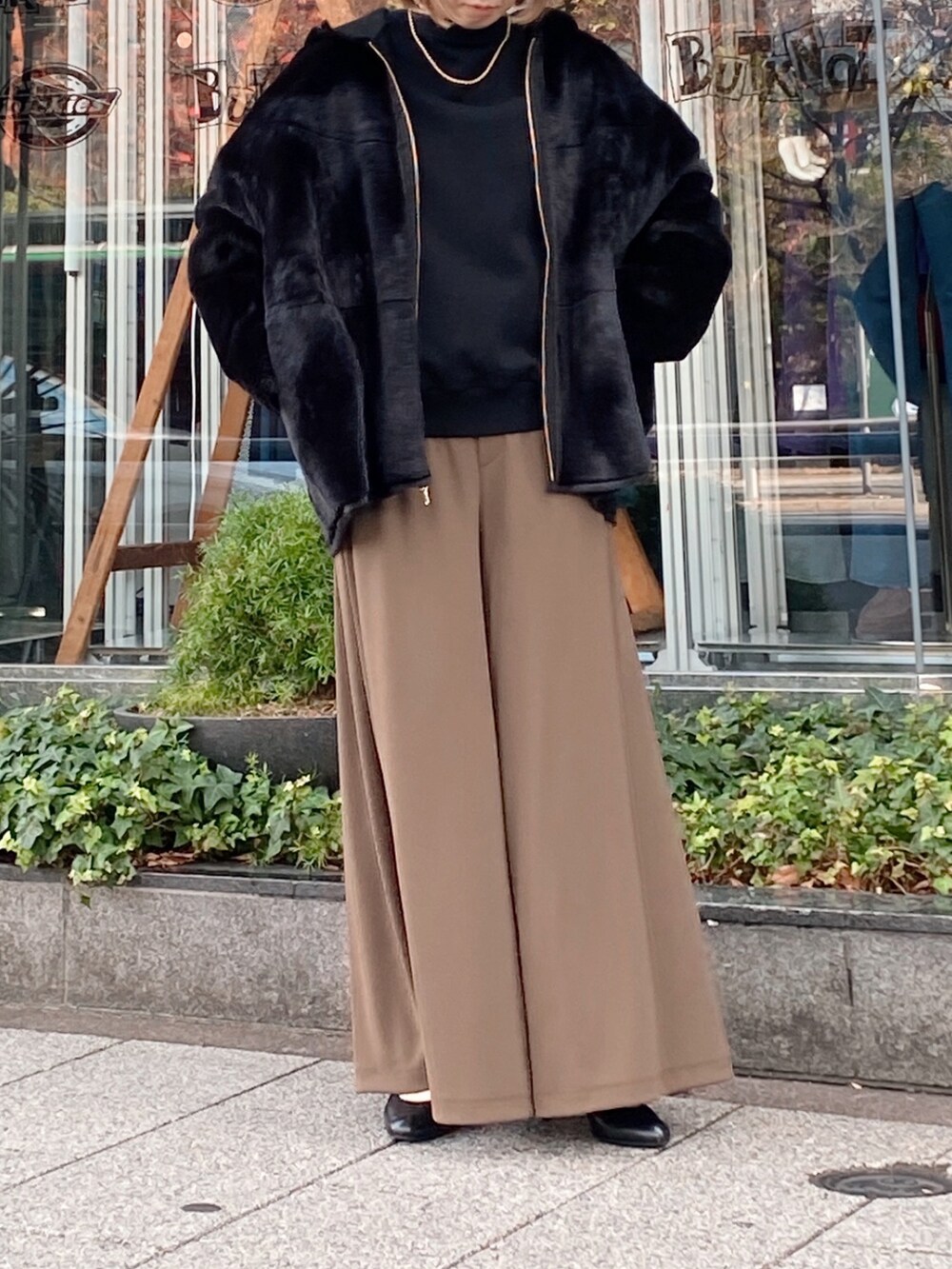 ブラック系のムートンコート、ブラック系のスウェット、グリーン系のその他パンツを着用したレディースの冬コーディネートの2枚目の写真