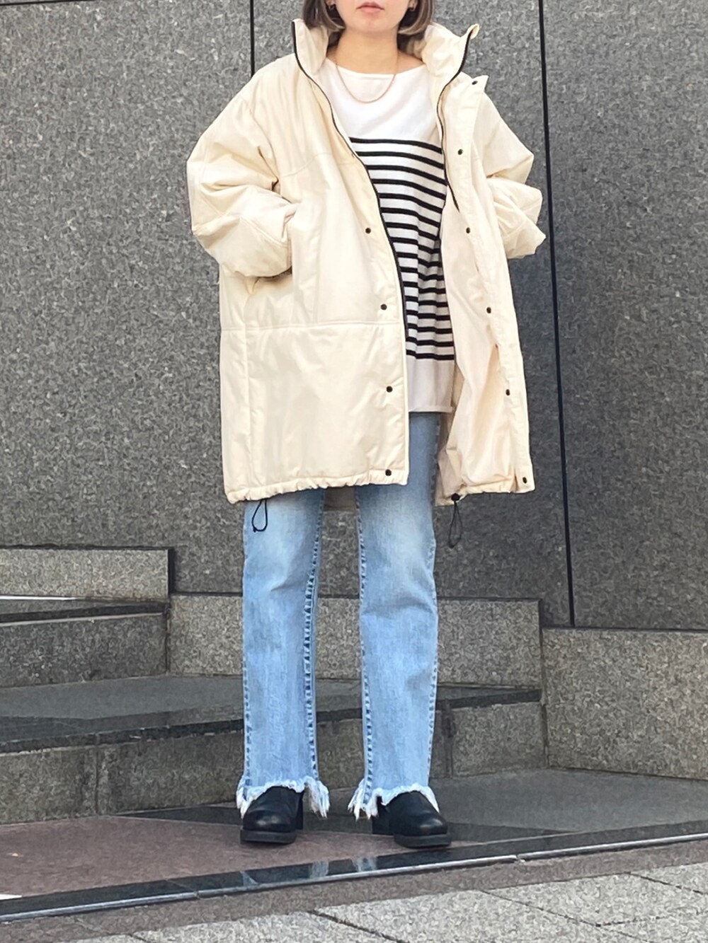 ブルー系のデニムパンツ、ホワイト系のブルゾン、ブラック系のニット/セーターを着用したレディースの秋コーディネートの2枚目の写真