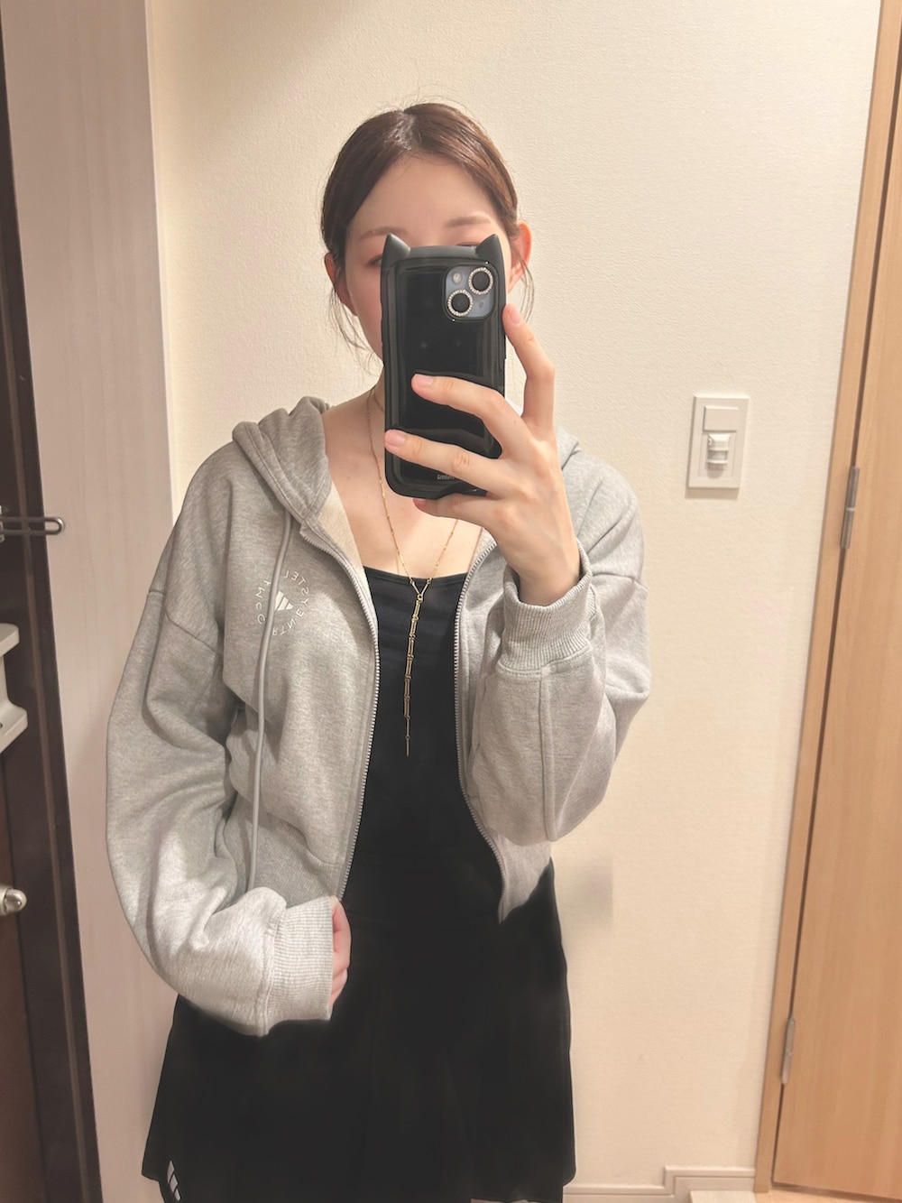 ブラック系のスカート、ブラック系のキャミソール、グレー系のパーカーを着用したレディースの夏コーディネートの2枚目の写真