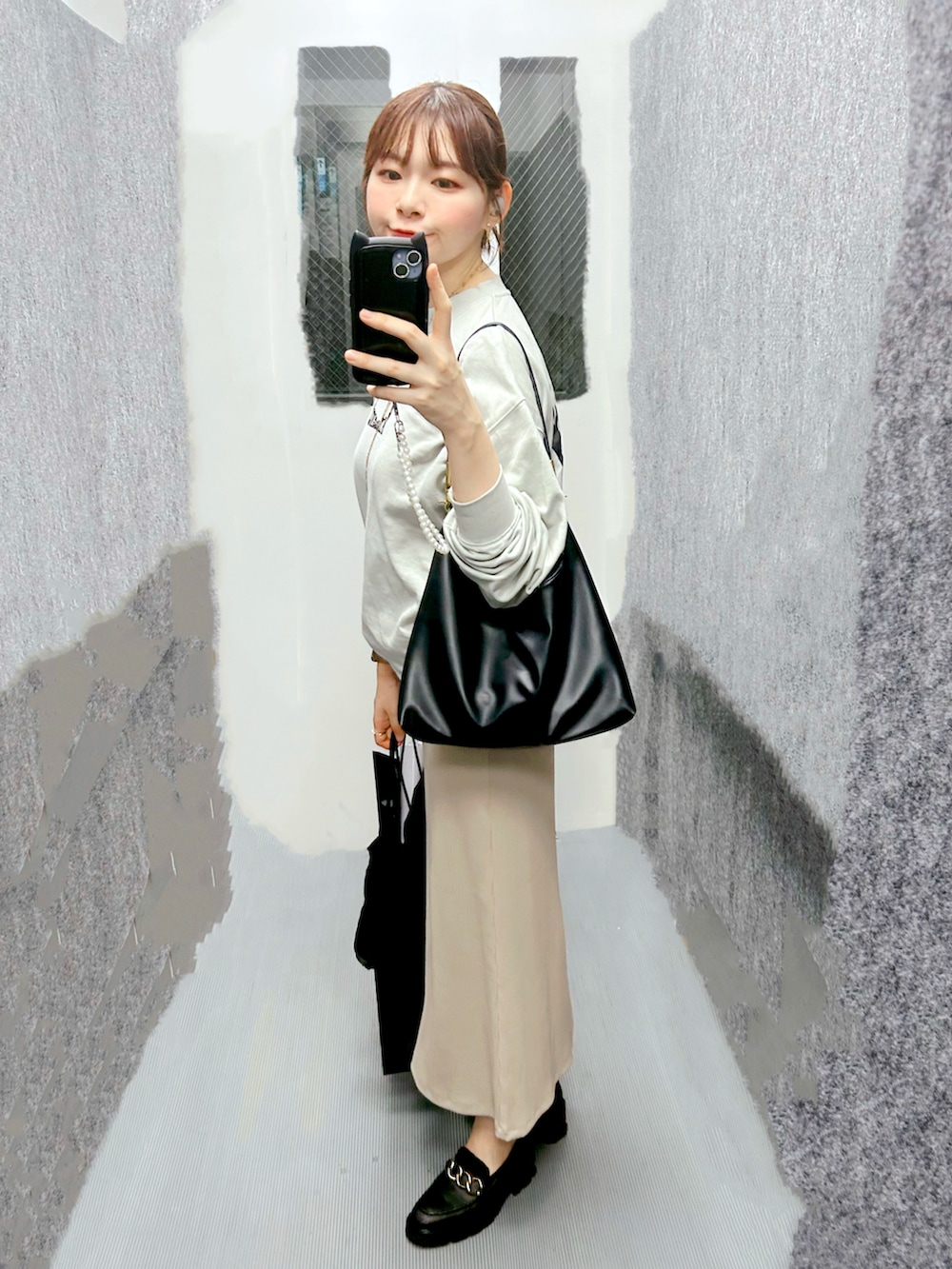 グリーン系のスウェット、ベージュ系のワンピース、ブラック系のローファーを着用したレディースの秋コーディネートの2枚目の写真