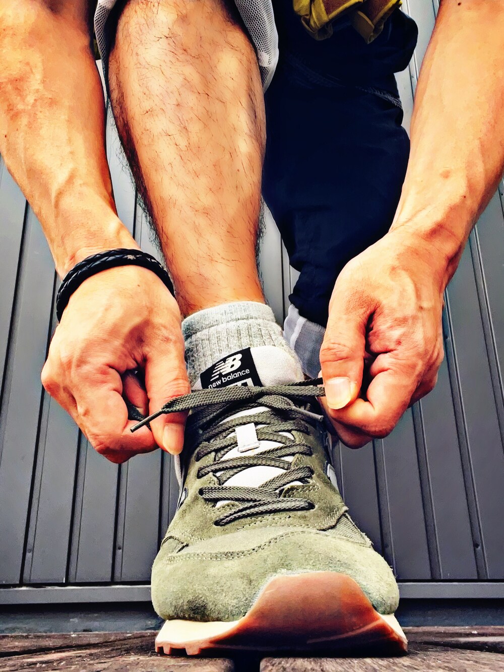 イエロー系のナイロンジャケット、ブルー系のTシャツ/カットソー、ベージュ系のタンクトップを着用したメンズの夏コーディネートの4枚目の写真