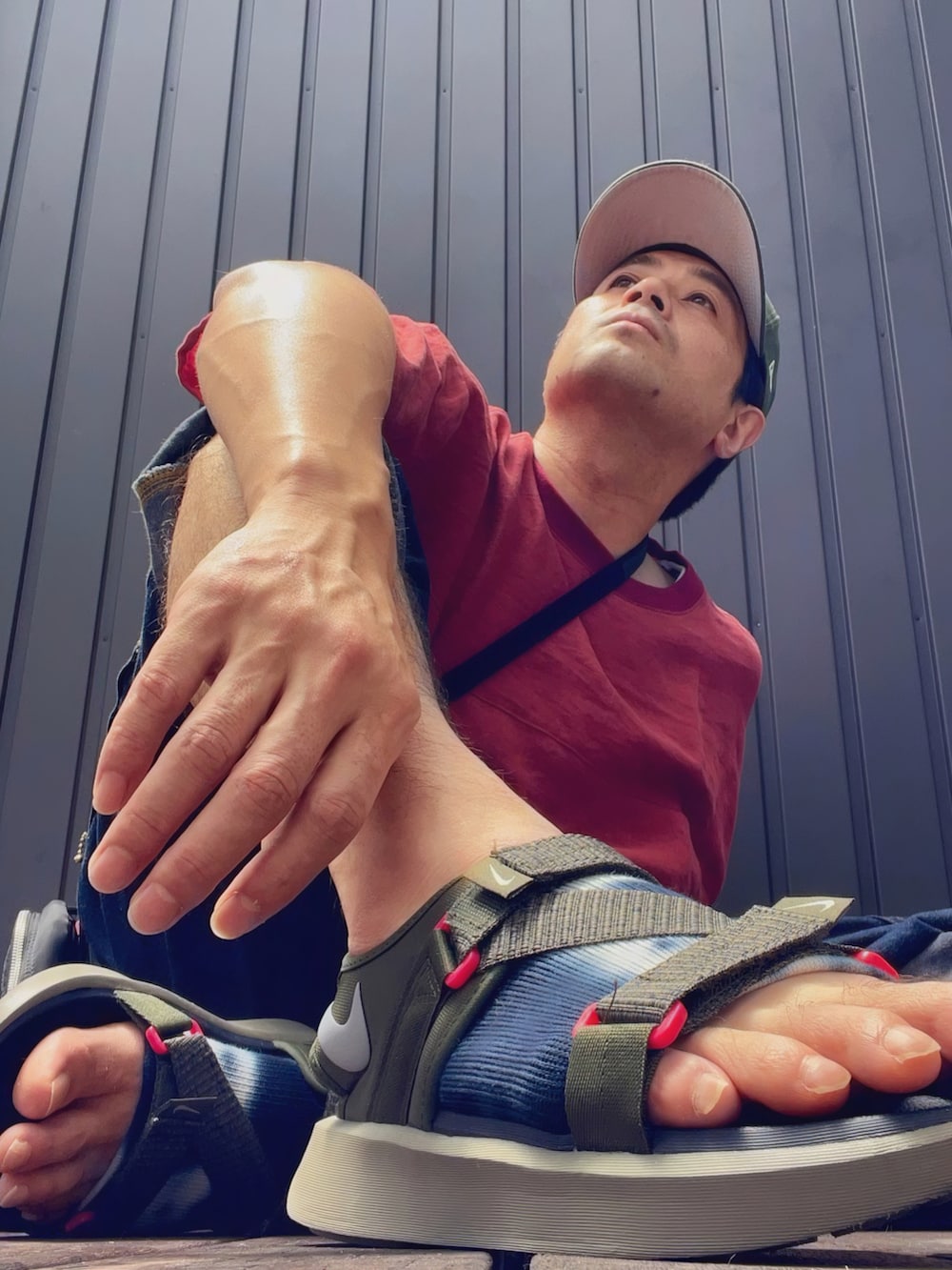 レッド系のTシャツ/カットソー、ブラック系のショルダーバッグ、その他のタンクトップを着用したメンズの夏コーディネートの5枚目の写真