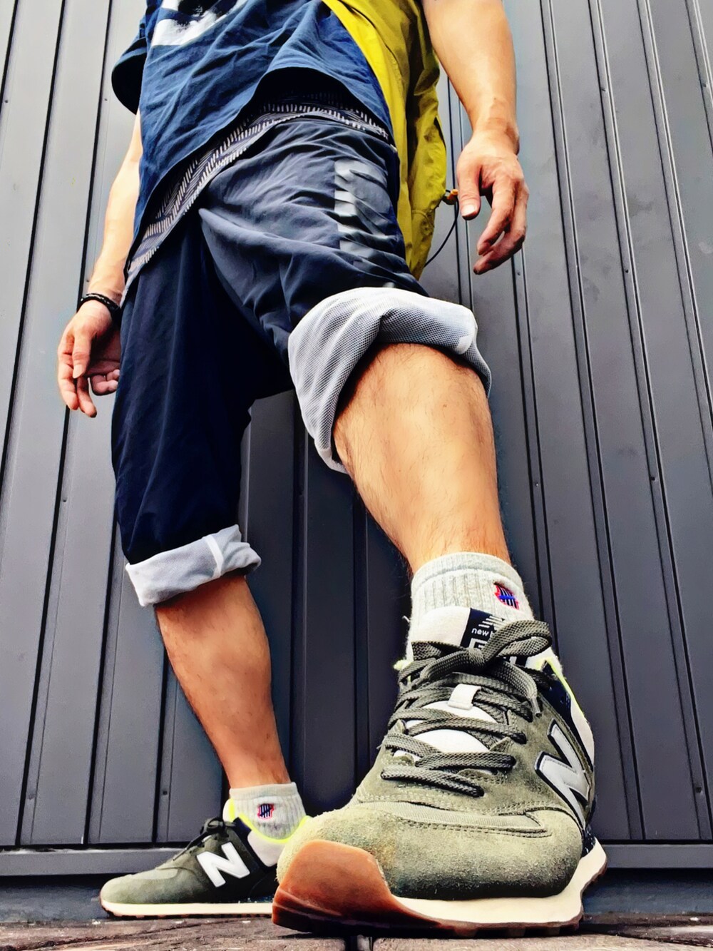 イエロー系のナイロンジャケット、ブルー系のTシャツ/カットソー、ベージュ系のタンクトップを着用したメンズの夏コーディネートの3枚目の写真