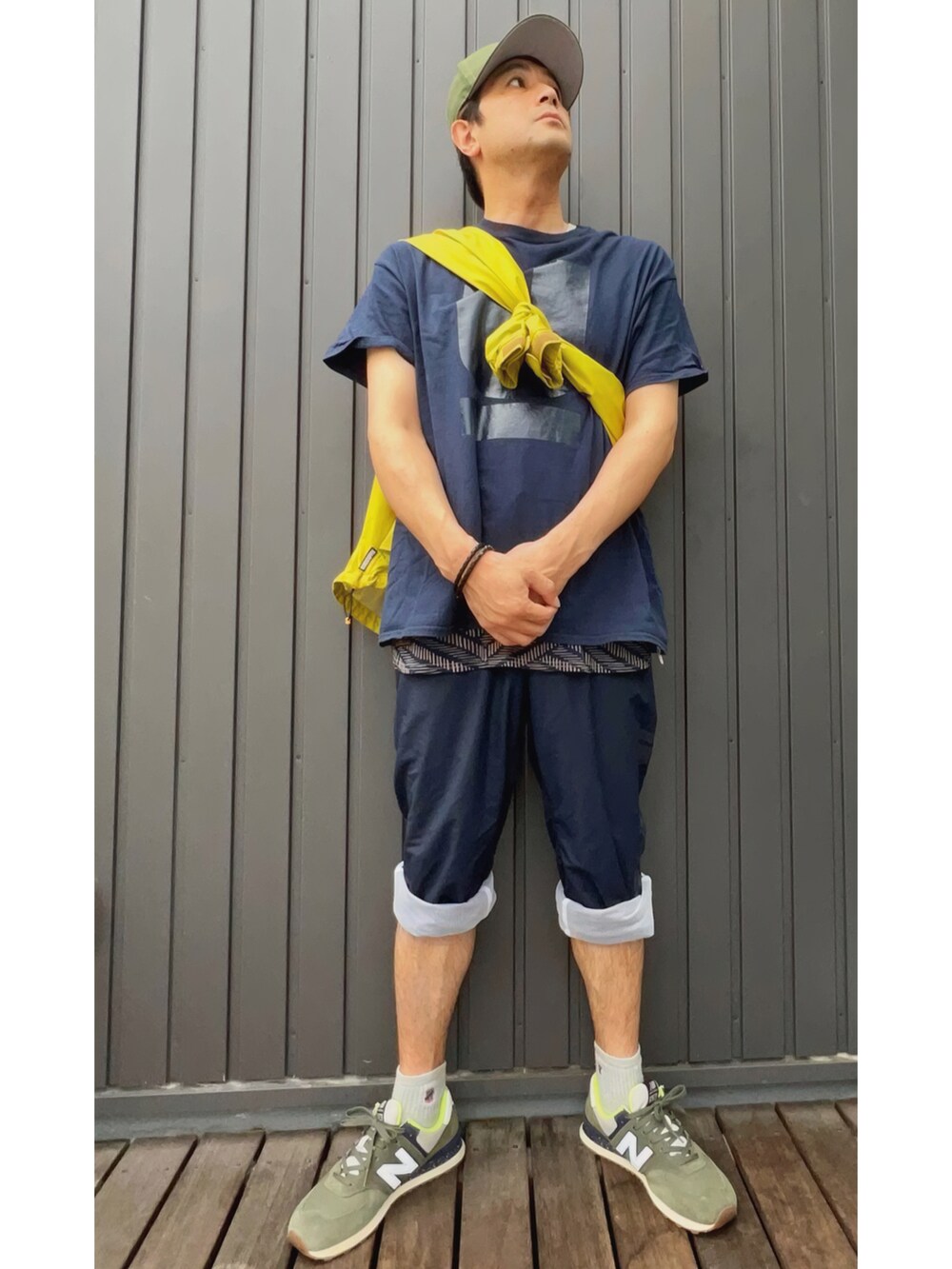 イエロー系のナイロンジャケット、ブルー系のTシャツ/カットソー、ベージュ系のタンクトップを着用したメンズの夏コーディネートの5枚目の写真