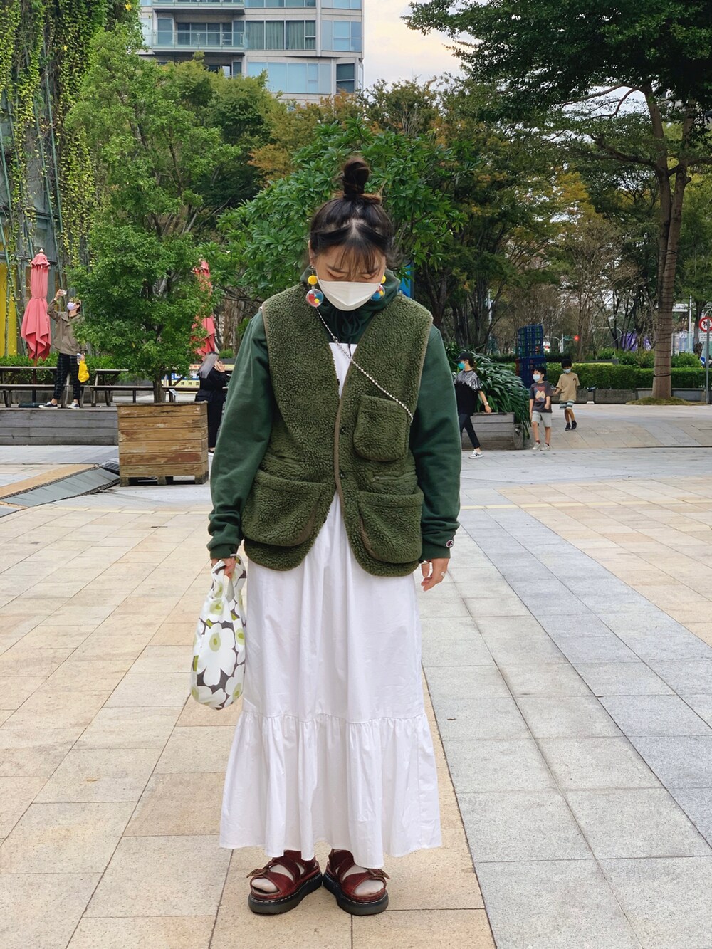 ホワイト系のワンピース、ブラウン系のサンダル、グリーン系のパーカーを着用したレディースの冬コーディネートの2枚目の写真