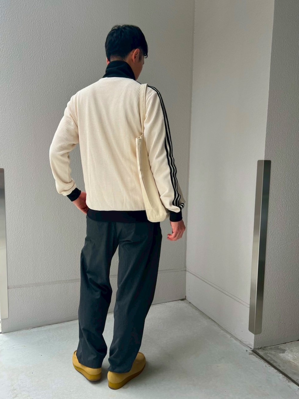 ホワイト系のジャージ、グレー系のスラックス、ベージュ系のモカシン/デッキシューズを着用したメンズの春コーディネートの3枚目の写真