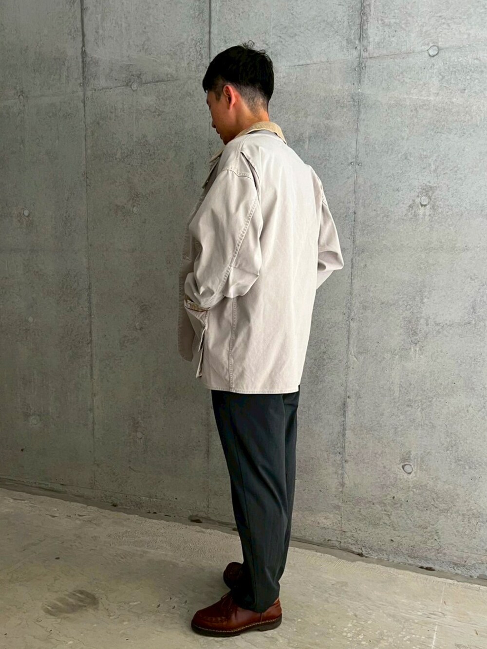 ホワイト系のカバーオール、ブラック系のTシャツ/カットソー、グレー系のスラックスを着用したメンズの春コーディネートの2枚目の写真
