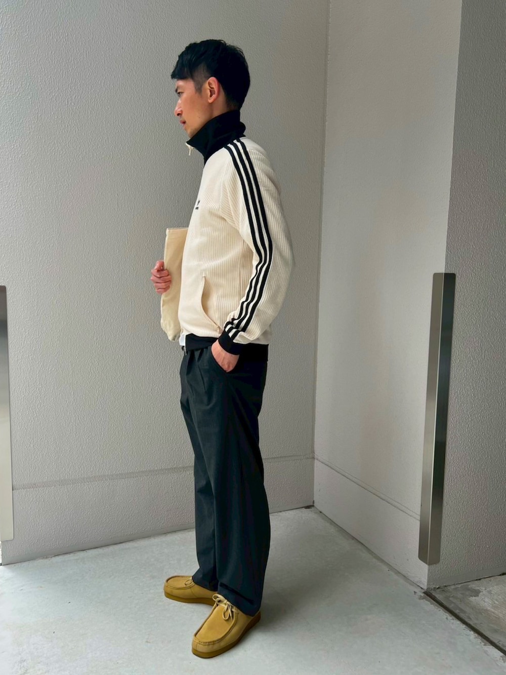 ホワイト系のジャージ、グレー系のスラックス、ベージュ系のモカシン/デッキシューズを着用したメンズの春コーディネートの2枚目の写真