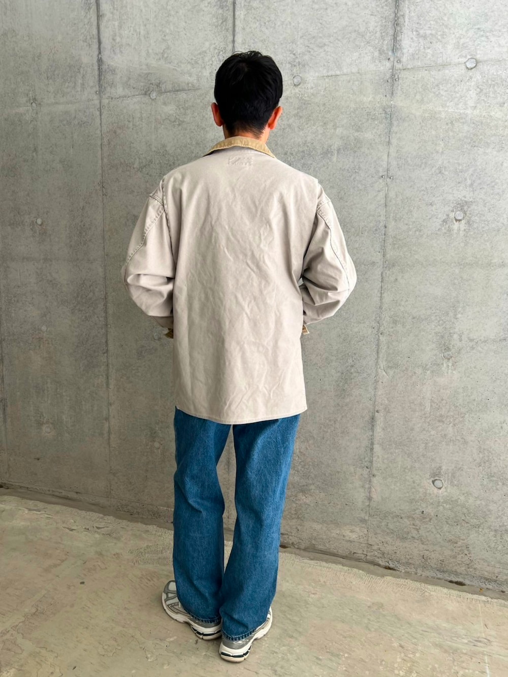 ホワイト系のカバーオール、ブルー系のデニムパンツ、シルバー系のスニーカーを着用したメンズの春コーディネートの3枚目の写真