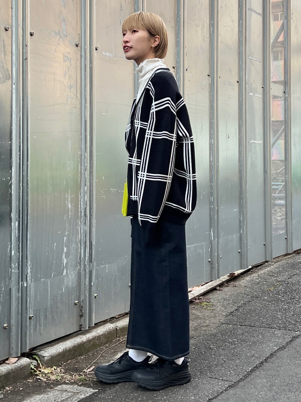 ブラック系のカーディガン/ボレロ、ブルー系のデニムスカート、グリーン系のショルダーバッグを着用したレディースの冬コーディネートの2枚目の写真