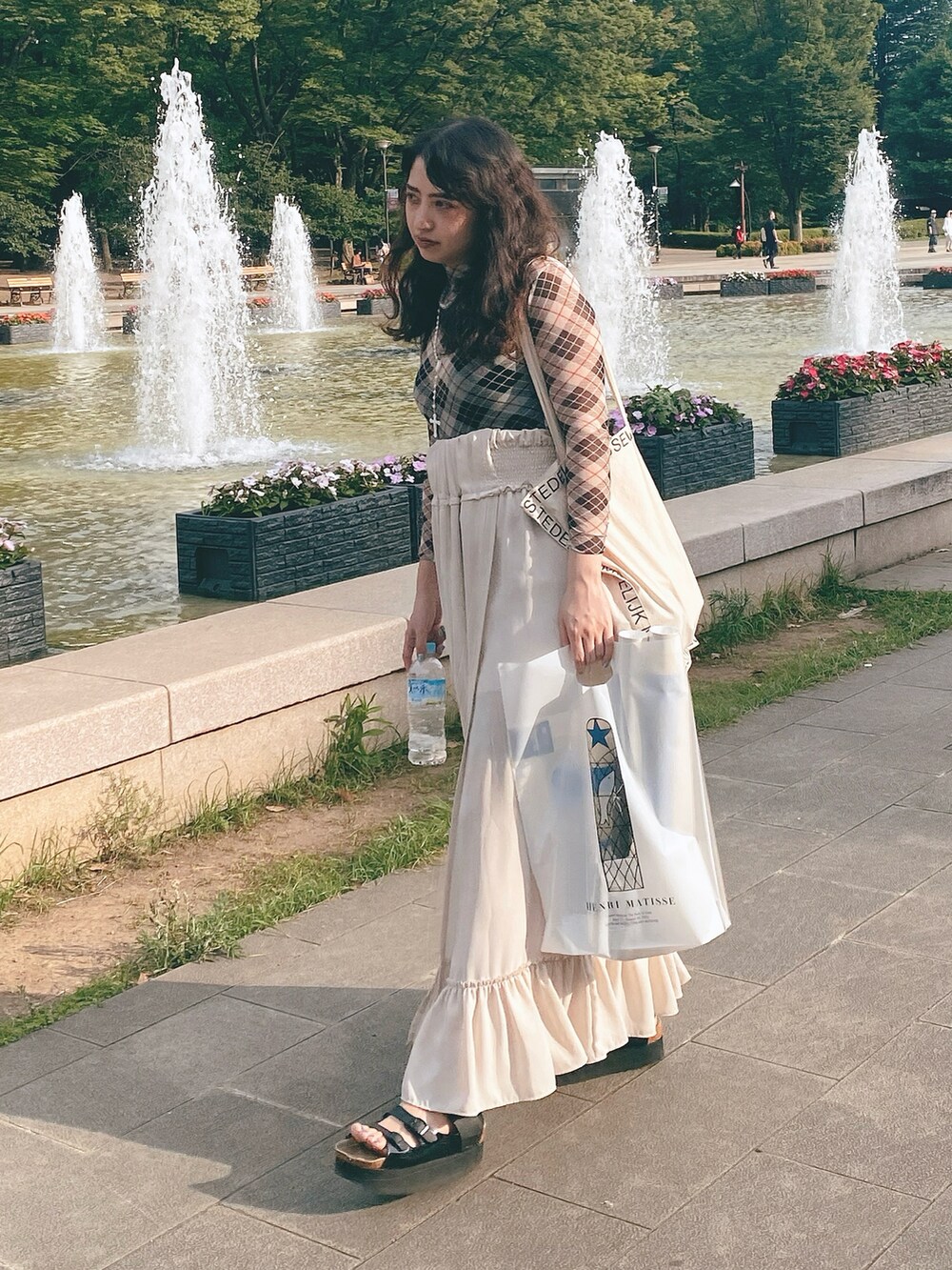 ホワイト系のスカート、ブラック系のサンダル、ホワイト系のトートバッグを着用したレディースの春コーディネートの2枚目の写真