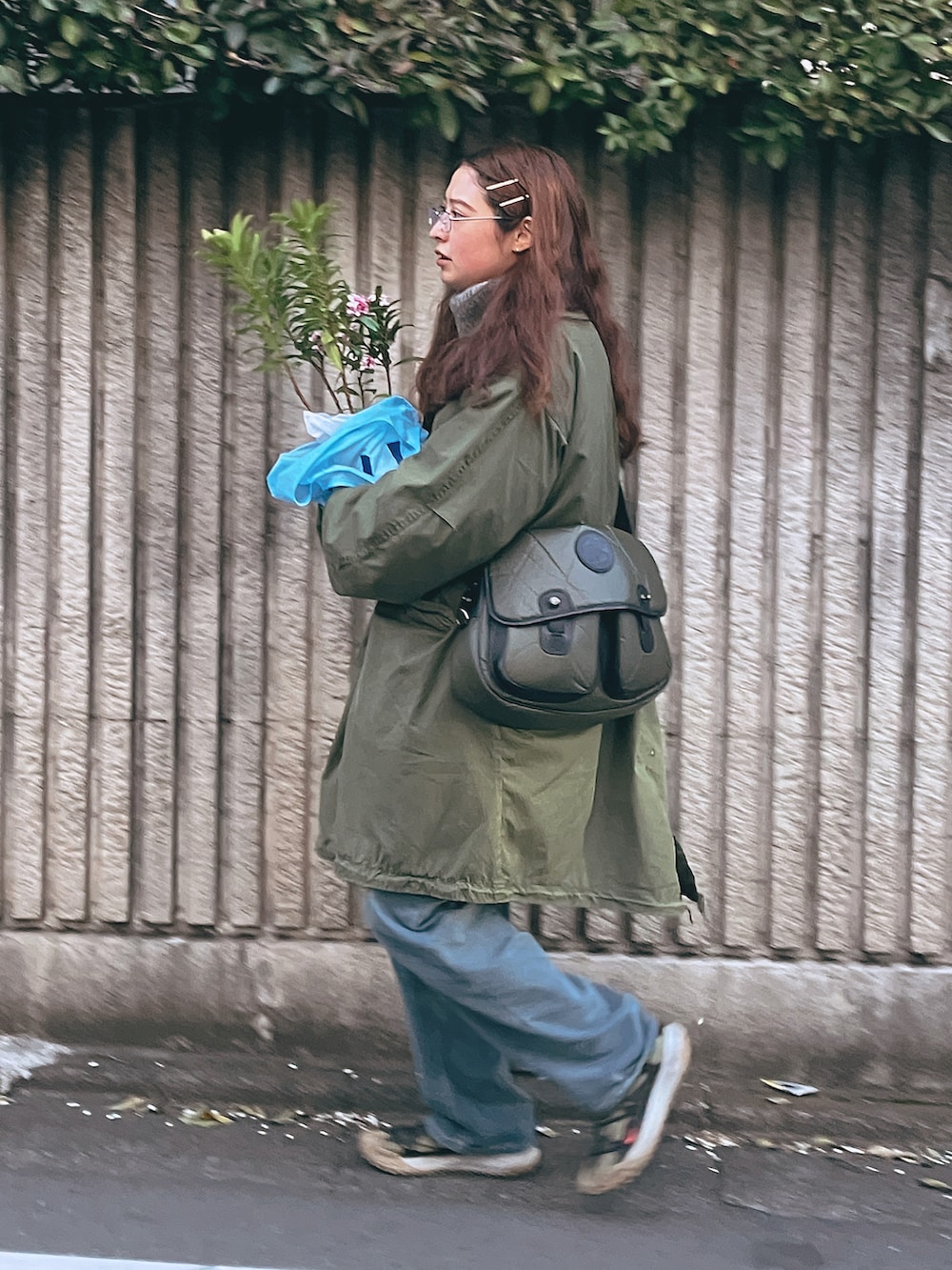 ブルー系のデニムパンツ、ブラウン系のスニーカー、グリーン系のショルダーバッグを着用したレディースの冬コーディネートの3枚目の写真