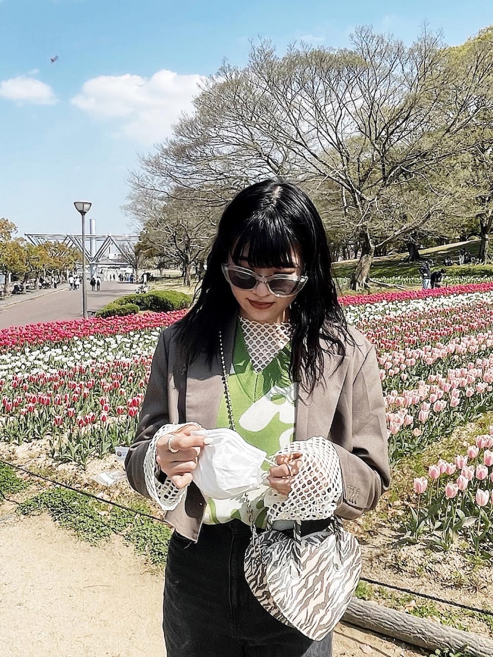 ブラック系のデニムパンツ、ブラック系のブーツ、グリーン系のベストを着用したレディースの春コーディネートの2枚目の写真