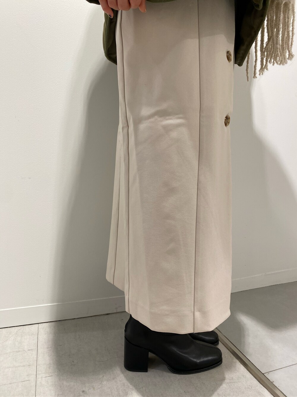 グリーン系のナイロンジャケット、ホワイト系のジャンパースカート、ブラック系のブーツを着用したレディースの秋コーディネートの4枚目の写真