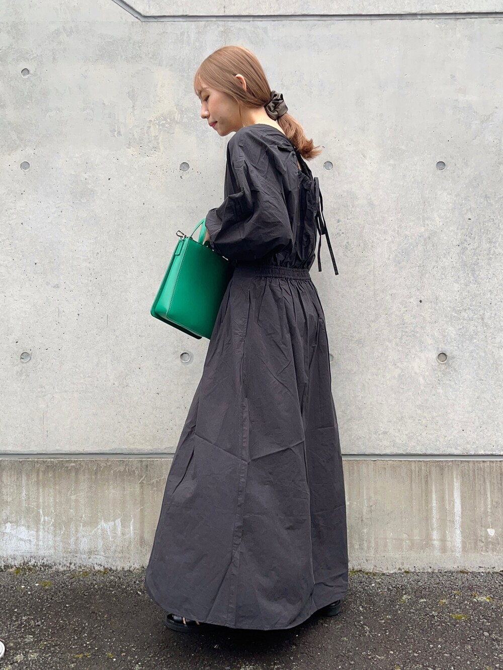 ブラック系のワンピース、グリーン系のトートバッグ、ブラック系のサンダルを着用したレディースの春コーディネートの2枚目の写真