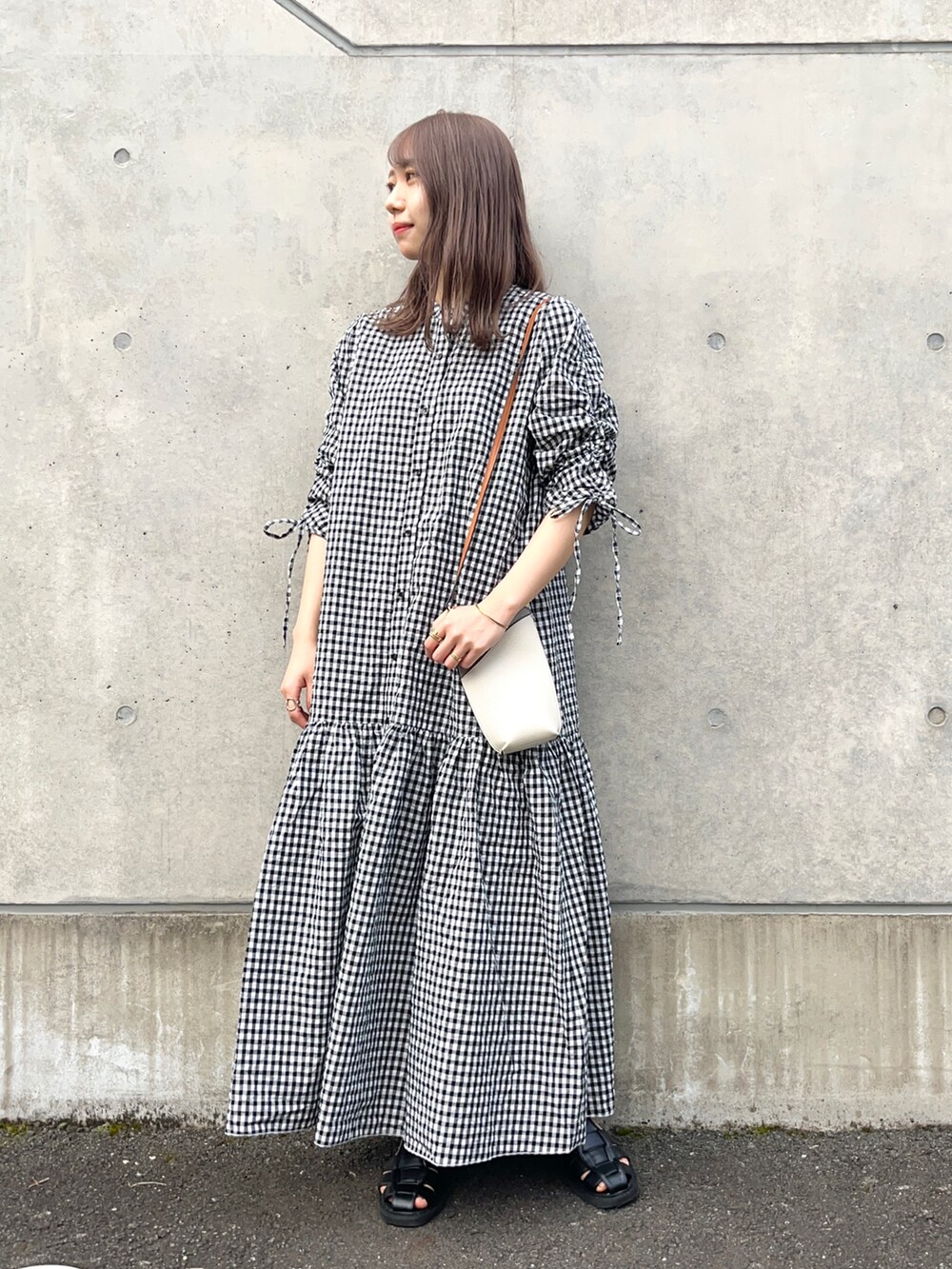 ブラック系のワンピース、ホワイト系のショルダーバッグ、ブラック系のサンダルを着用したレディースの春コーディネートの3枚目の写真