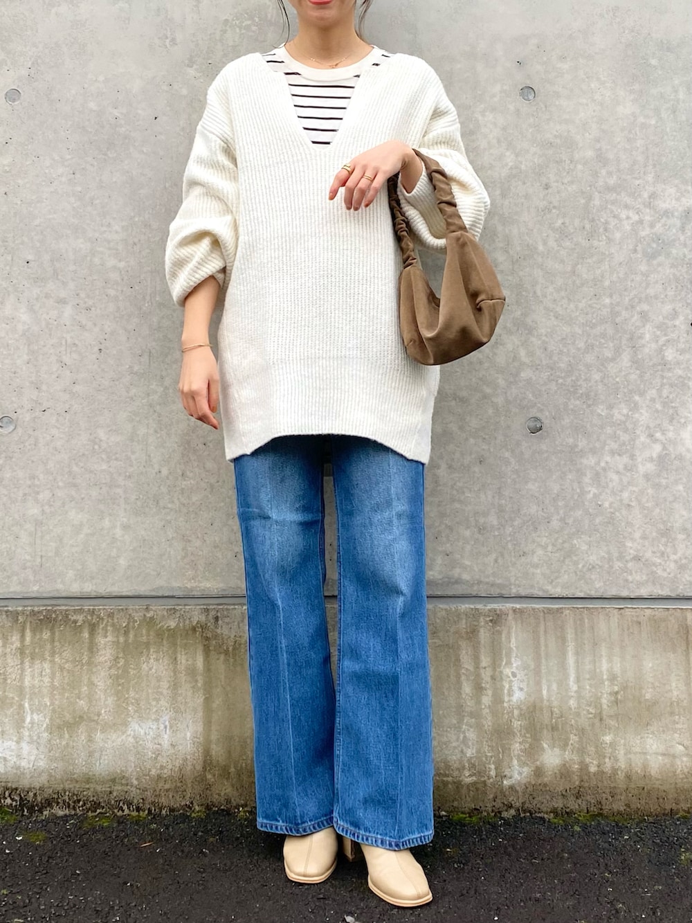 ホワイト系のニット/セーター、ブルー系のデニムパンツ、ベージュ系のブーツを着用したレディースの冬コーディネートの2枚目の写真