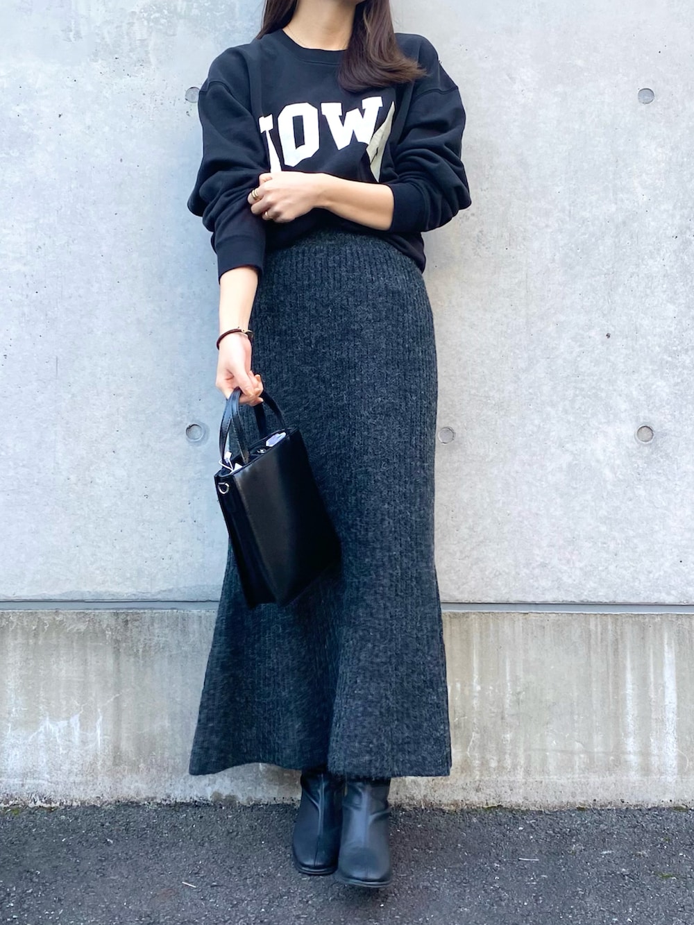 ブラック系のスカート、ブラック系のショルダーバッグ、ブラック系のブーツを着用したレディースの秋コーディネートの2枚目の写真