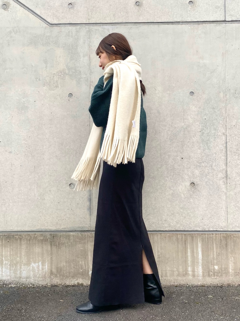 グリーン系のニット/セーター、ブラック系のその他シューズ、ホワイト系のマフラーを着用したレディースの冬コーディネートの5枚目の写真