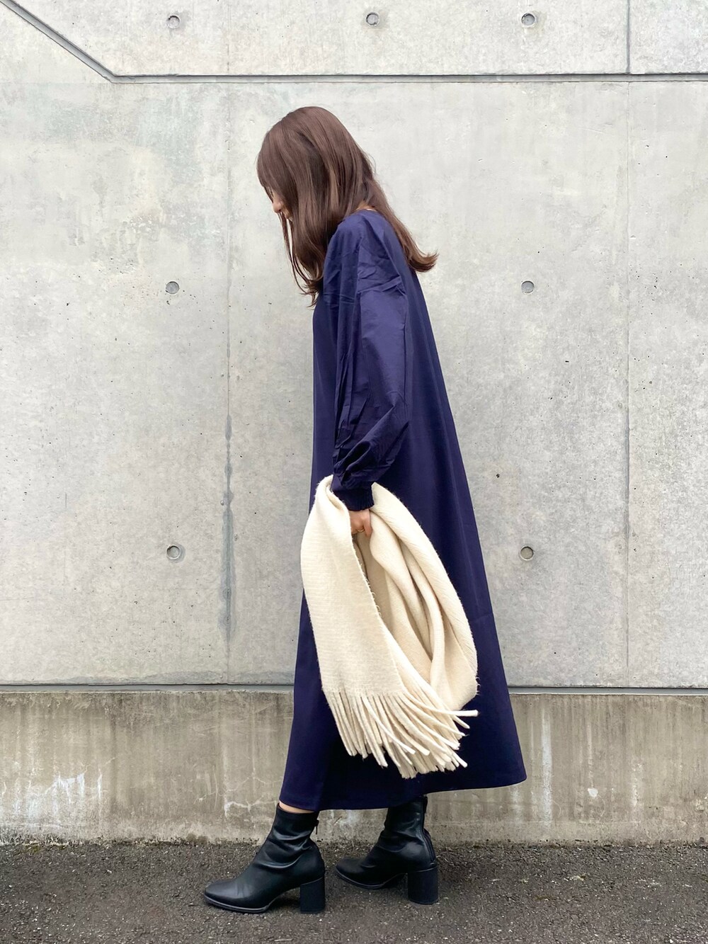 ブルー系のワンピース、ブラック系のブーツ、ホワイト系のマフラーを着用したレディースの秋コーディネートの2枚目の写真