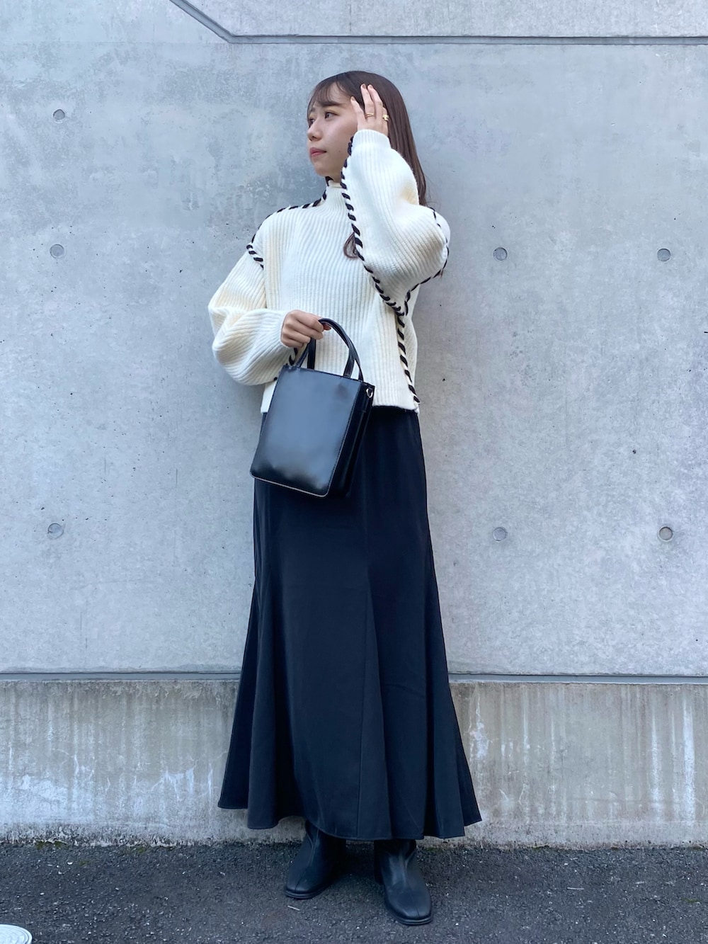 ホワイト系のニット/セーター、ブラック系のスカート、ブラック系のブーツを着用したレディースの秋コーディネートの4枚目の写真