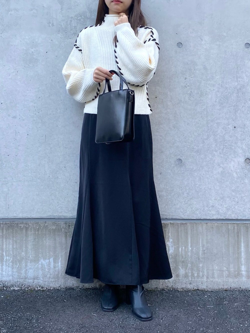 ホワイト系のニット/セーター、ブラック系のスカート、ブラック系のブーツを着用したレディースの秋コーディネートの2枚目の写真