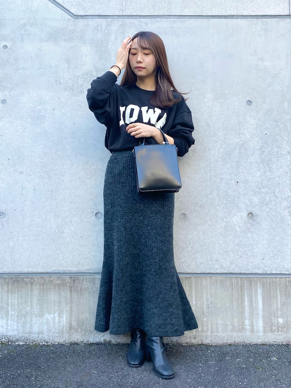 ブラック系のスカート、ブラック系のショルダーバッグ、ブラック系のブーツを着用したレディースの秋コーディネートの4枚目の写真